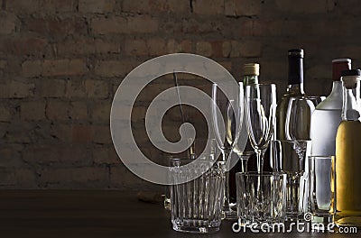 Empty clean glasses for wine, champagne, cocktails and bottles of alcoholic driks on the table agaisnt brick wall.Night at the bar Stock Photo