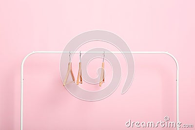 empty clothes hangers on a wardrobe rack on a colored background. Stock Photo