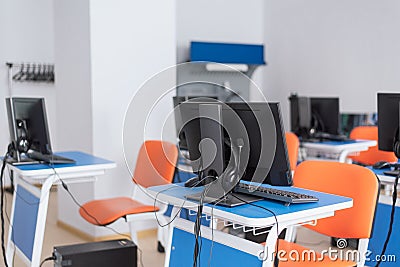 Empty computer classroom with bright blue desks and orange chairs. teaching children programming Stock Photo