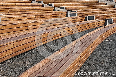 Empty contemporary wooden benches in open air outdoor city public event space.Modern urban public vandal proof resting furniture. Stock Photo