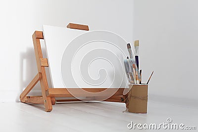 Empty copy space canvas on wood easel and paintbrush in artistic workshop interior Stock Photo