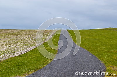 Empty countryside road running between green pastures Stock Photo