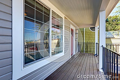 Empty covered porch with black metal railings and columns. Stock Photo