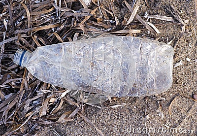 Empty crushed plastic bottle on sand Stock Photo