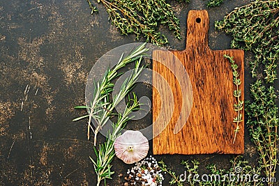 An empty cutting board with a frame of fresh herbs of thyme and rosemary. Top view, space for text or menu. Stock Photo