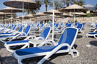 Empty deckchairs and umbrellas with a thatched roof on the beach Stock Photo