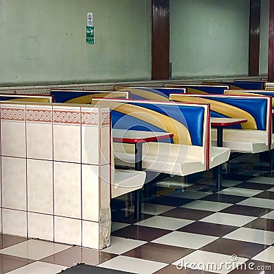 Empty diner area with white blue and yellow seats and brown and white floor tiles Stock Photo