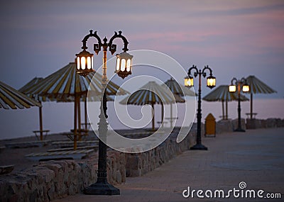 Empty embankment with straw umbrellas and streetlights in Dahab at night Stock Photo