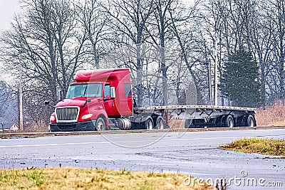 An Empty Flatbed Tractor Trailer Drives in Mixed Winter Weather Stock Photo