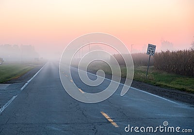 Empty foggy road at sunrise Stock Photo