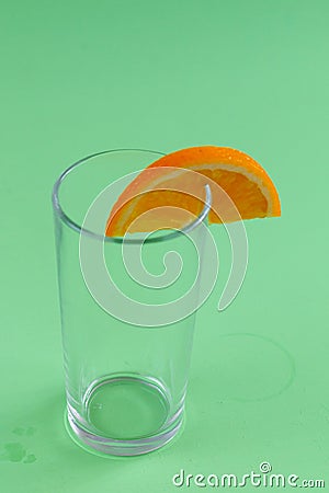 Empty glass with an orange slice isolated on green background Stock Photo