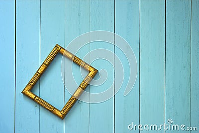 An empty golden frame hangs askew on a plank wall Stock Photo