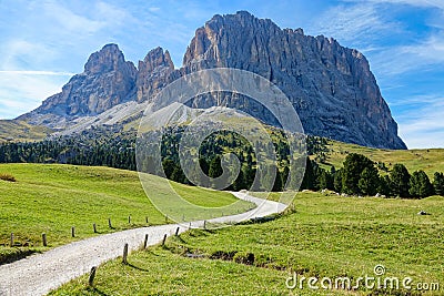 Empty gravel road leads towards the majestic rocky mountain in the Dolomites. Stock Photo