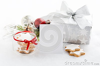 Empty greeting card and christmas gift box in silver wrapping paper over a white fluffy background. A jar full of star cookies. C Stock Photo