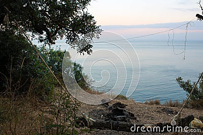 Empty home-made swing, an extinct fire. Seashore in the evening Stock Photo