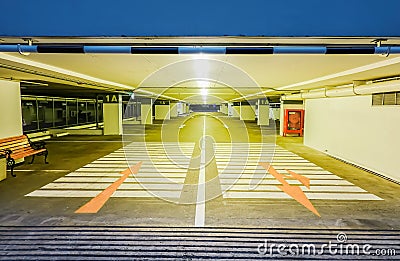 Empty illuminated underground car parking interior under modern mall and arrows on floor Stock Photo
