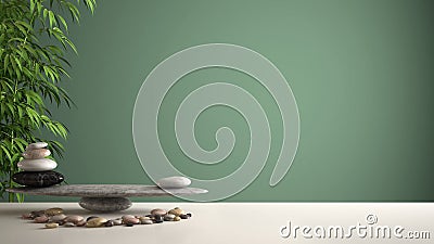 Empty interior design feng shui concept zen idea, white table or shelf with pebble balance and green bamboo, over green background Stock Photo