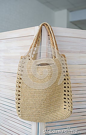 Empty knitted bag hanging on wooden door. Ad and buy concept Stock Photo