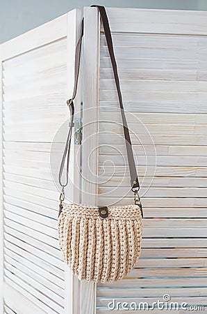 Empty knitted purse hanging on wooden door. Ad and buy concept Stock Photo
