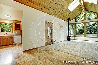 Empty living room with connected kitchen, vaulted wood ceiling, and large windows. Stock Photo