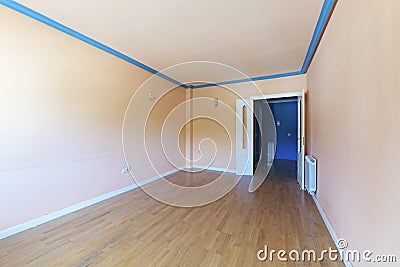 Empty living room with light peach painted walls and ceiling, blue plaster cornices and wooden flooring Stock Photo