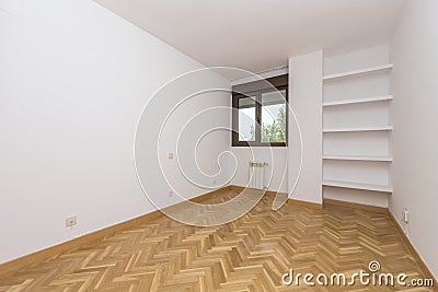Empty living room with plain white painted walls, herringbone French oak parquet flooring and plaster shelves on one wall Stock Photo