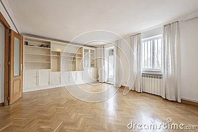 Empty living room with smooth white painted walls, French oak parquet floors laid in a herringbone pattern and custom-made white Stock Photo