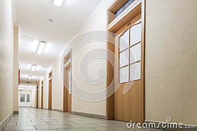 Empty long corridor. Empty office corridor with many doors of light wood Stock Photo