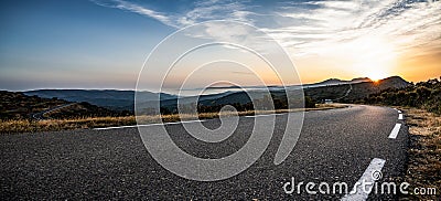 Empty long mountain road to the horizon on a sunny summer day at bright sunset Stock Photo