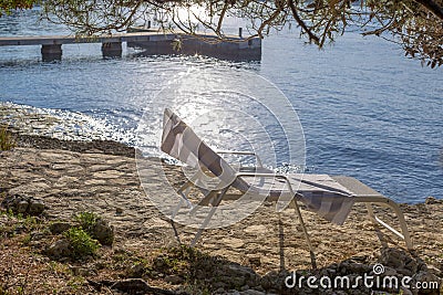 Empty lounger on the rocky beach. Stock Photo