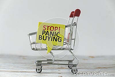 An empty miniature shopping cart with a yellow speech bubble written with advice of Stop! panic buying in reflect to current Stock Photo