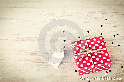 Empty note tied over a red dotted gift box. Wooden background. Vintage style. Stock Photo