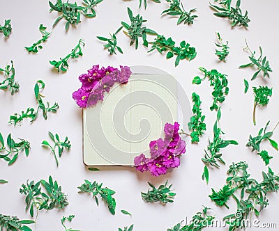 Empty notebook decorated purple flowers on a white background, top view. Notepad decorated with green leaves and violet. Flat lay. Stock Photo