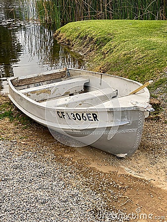 Empty old decaying metal row boat grounded at a swamp lake pond Stock Photo