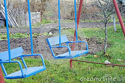 Empty Old wooden children blue swing for two persons in the backyard in autumn Stock Photo