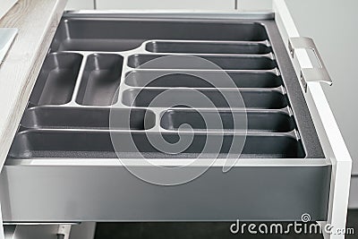 Empty open drawer of white kitchen set with black cutlery organizer tray, side view. Storage organization system Stock Photo