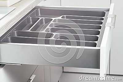 Empty open drawer of white kitchen set with black cutlery organizer tray, side view. Storage organization system Stock Photo