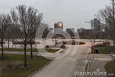 Empty parking lot with barren trees and highrises in the background Stock Photo