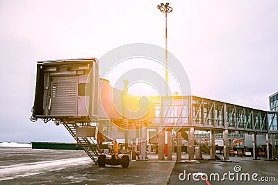 Empty passenger boarding bridge at the winter airport apron in sun light Stock Photo