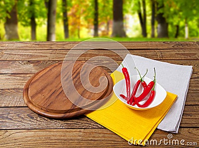 Empty pizza desk, red hot pepper, yellow and white napkin on wooden table on blurred forest background Stock Photo