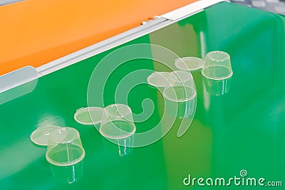 Empty plastic cups moving on green conveyor belt at exhibition Stock Photo