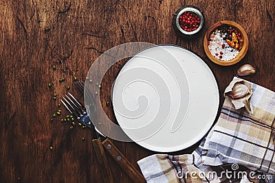 Empty plate with forks, napkin and spices on vintage wooden kitchen table, rustic setting, ready to serve, top view Stock Photo