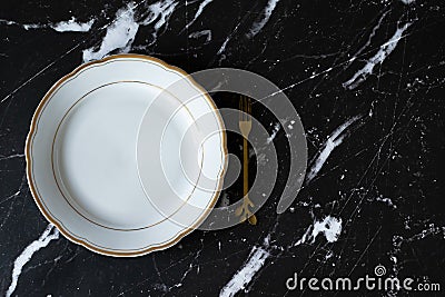 Empty plate with golden fork on dark granite background with copy space, top view Stock Photo