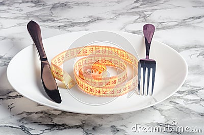 Empty plate with measuring tape, knife and fork. Stock Photo