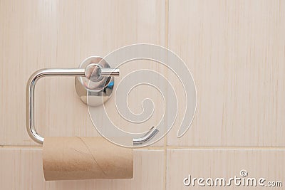 Empty roll on toilet paper holder with green white wall in background Stock Photo