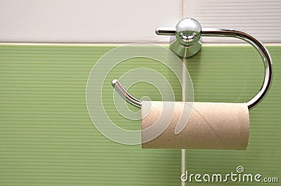 Empty roll on toilet paper holder with white and green tiles in background Stock Photo