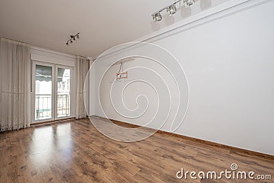 Empty room of a loft apartment with white painted walls, plaster moldings on the ceiling and exit to a terrace with aluminum and Stock Photo