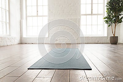 Empty room in yoga studio, unrolled yoga mat on floor Stock Photo