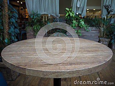 Empty round wooden table in a restaurant on the background of green plants Stock Photo