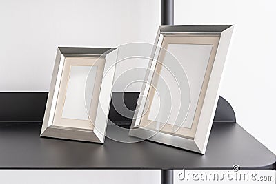 Empty silver small portrait frames, blank canvas, picture mock up, living room shelf Stock Photo